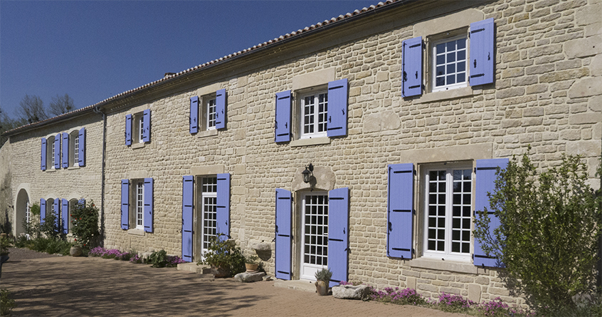 Maison en pierre avec des volets en composite bleus