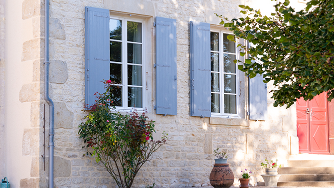 volets bleus sur une maison en pierre